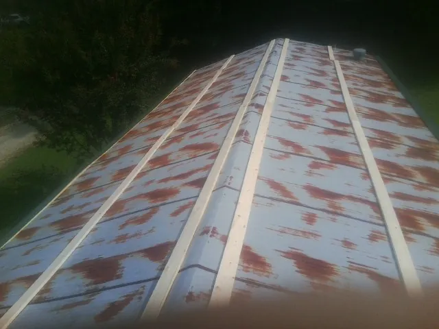 Rusted metal roof panels with new wood purlins before replacement — Storm Damage Roof Repair in Grand Ledge by Roofing Brothers