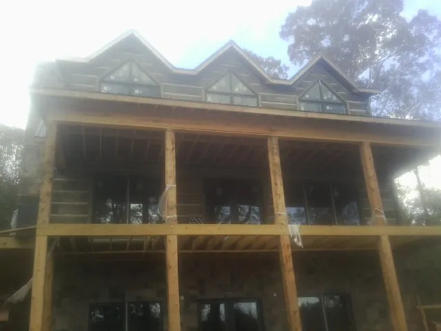 Dormers and porch framing on a large log home under construction — Roof Coating work by our crew in Grand Ledge