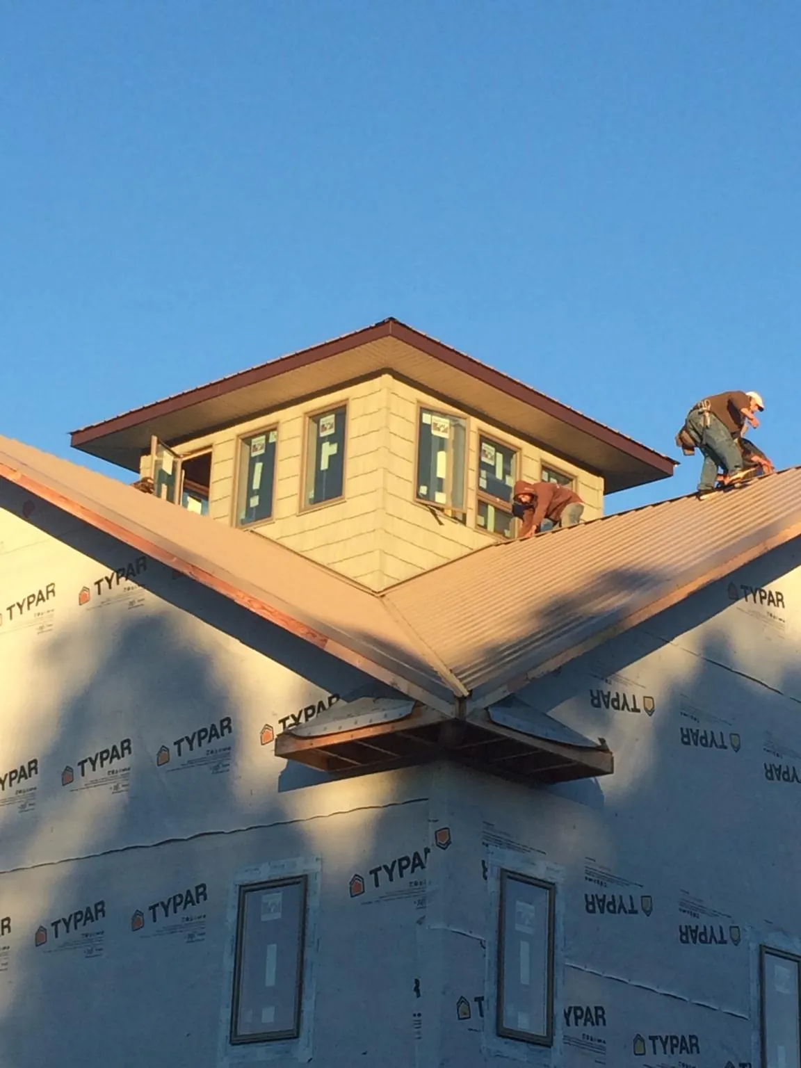 Roofers working around a rooftop cupola on a new metal roof at sunset — Roof Waterproofing in Grand Ledge by Roofing Brothers